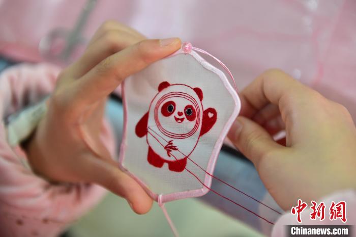圖為一名小學(xué)生正在繡制2022年北京冬奧會吉祥物“冰墩墩”形象。　喻云亮 攝
