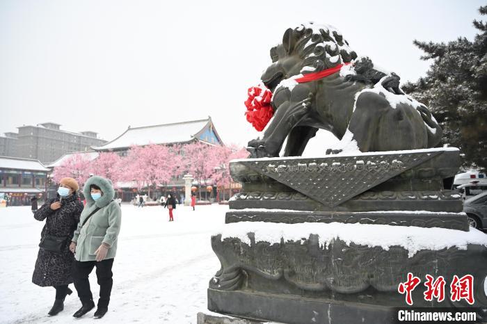 2月13日，民眾在呼和浩特市大召?gòu)V場(chǎng)雪中漫步?！⑽娜A 攝