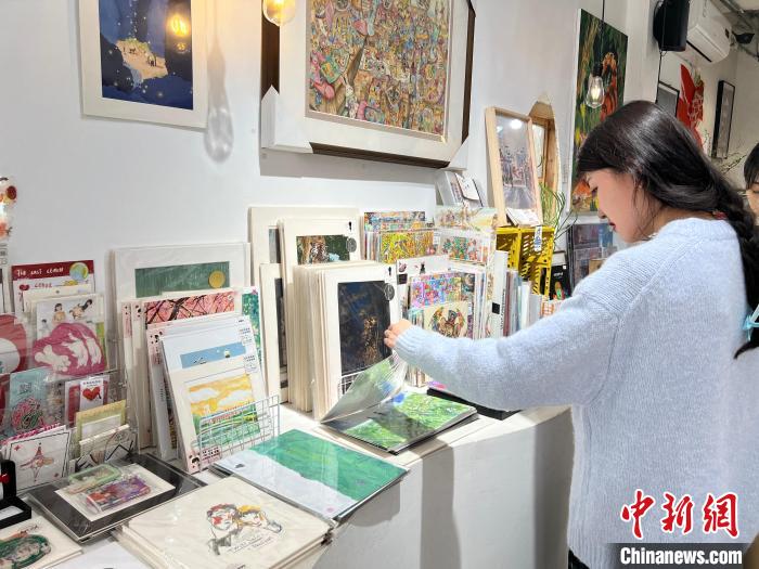 圖為藝術(shù)品商店內(nèi)，顧客挑選插畫作品。　鐘旖 攝