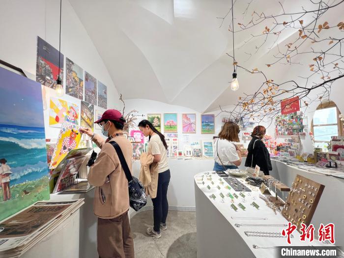 圖為藝術(shù)品商店內(nèi)，顧客挑選插畫作品?！＄婌?攝