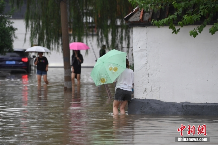 7月31日，市民行走在雨中的北京房山區(qū)瓦窯頭村。北京市氣象臺當日10時發(fā)布分區(qū)域暴雨紅色預(yù)警信號。北京市水文總站發(fā)布洪水紅色預(yù)警，預(yù)計當日12時至14時，房山區(qū)大石河流域?qū)⒊霈F(xiàn)紅色預(yù)警標準洪水。<a target='_blank' href='/'><p  align=
