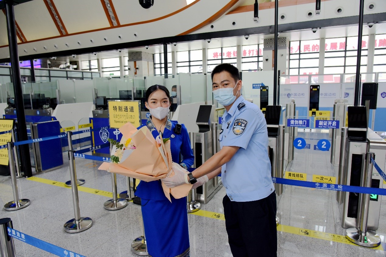 磨憨出入境邊防檢查站民警為中老鐵路第100萬名出入境旅客，D888次國際旅客列車?yán)蠐爰藙?wù)員森達(dá)拉·妮緹婭（Sengdala Nitiya），送上鮮花。黃遠(yuǎn)飛 攝