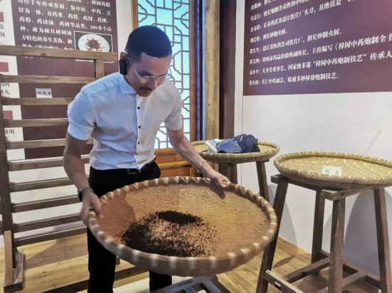 2023“一帶一路”媒體合作論壇聯(lián)合采訪團團員在非遺文化展示館體驗中藥炮制技藝。（本報記者 黃超攝）