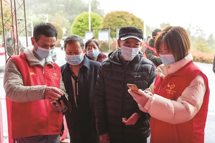 長(zhǎng)沙縣黨員志愿者正在幫助參與核酸檢測(cè)的群眾掃描“場(chǎng)所碼”。劉思源 攝