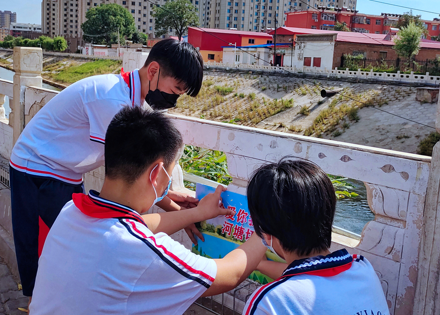 徐水小學(xué)學(xué)雷鋒志愿者在瀑河河邊張貼防溺水警示標(biāo)語。 徐水區(qū)委宣傳部供圖
