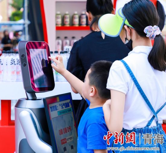 圖為一名小朋友正在和機(jī)器人“志愿者”進(jìn)行互動(dòng)。 沐聞 攝