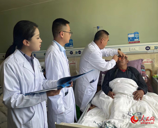 董光明（左三）帶領(lǐng)醫(yī)生對患者進(jìn)行術(shù)前檢查。人民網(wǎng)記者 杜燕飛攝