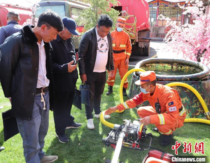 圖為森林消防員為護(hù)林員講解滅火裝備的使用方法?！〔际猩窒乐ш?duì) 供圖