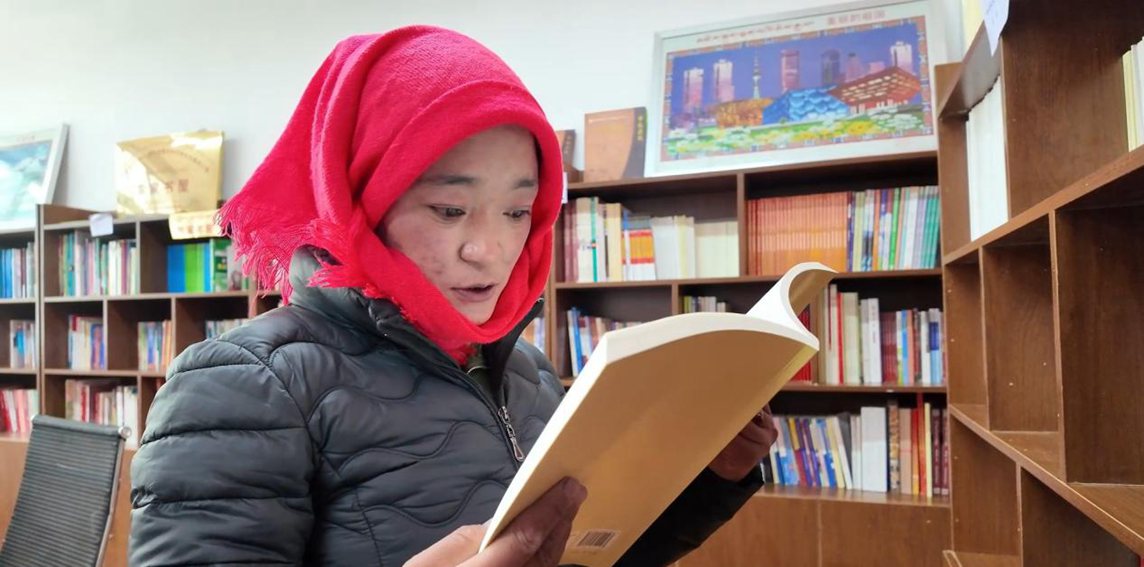 一名婦女正在認真閱讀書籍。申扎縣融媒體中心供圖