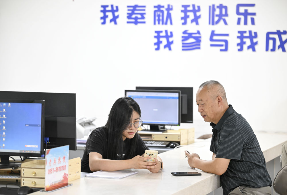 2024年6月20日，在寧夏銀川市金鳳區(qū)長城花園社區(qū)黨群服務(wù)中心，工作人員幫助居民辦理業(yè)務(wù)。圖片來源 新華社
