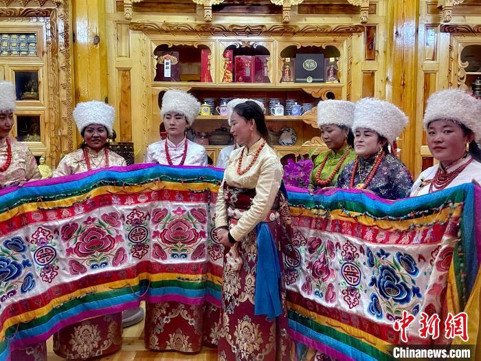 圖為女性展示村民自發(fā)繡制的“百米五彩哈達(dá)”?！±钣穹?攝