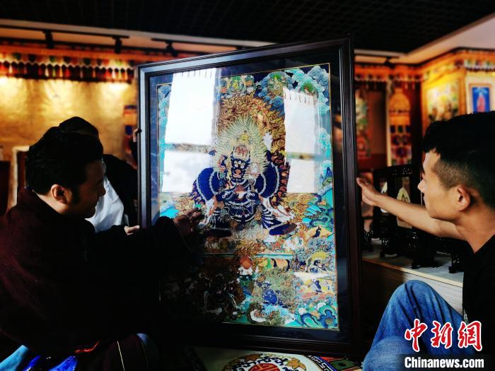 圖為久美尖措(左)與徒弟們展示唐卡作品?！?zhí)砀?攝