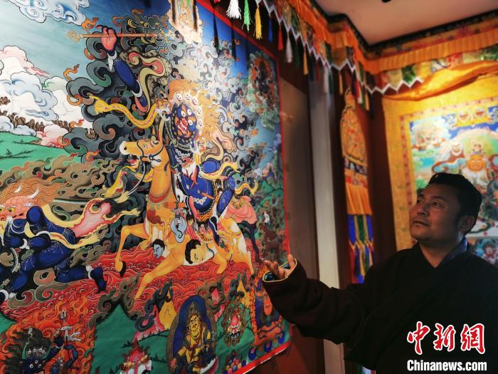 圖為久美尖措展示唐卡作品?！?zhí)砀?攝