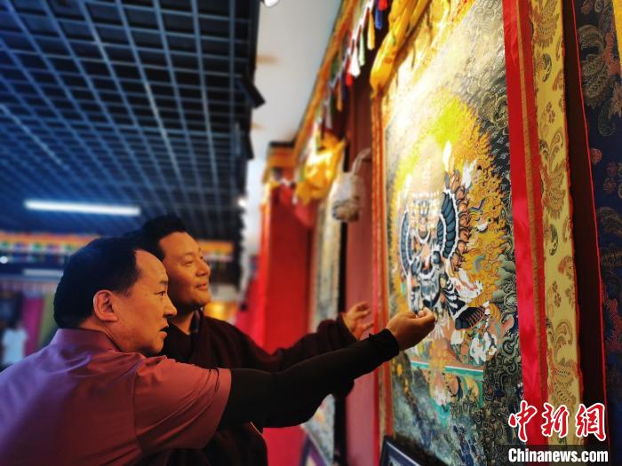 圖為久美尖措展示唐卡作品?！?zhí)砀?攝