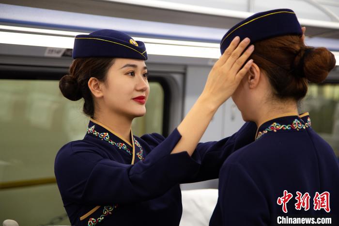 圖為青藏鐵路西格段“復(fù)興號”動(dòng)車組乘務(wù)員互相整理新制服。　李磊 攝