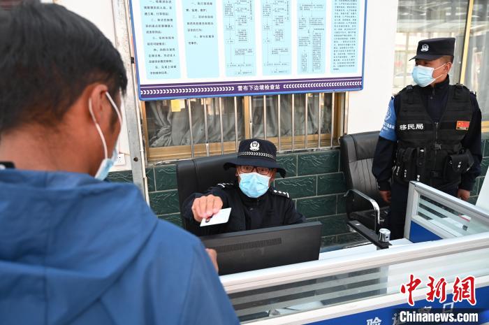 圖為移民管理警察登記完身份信息后將證件歸還給行人?！≮w朗 攝