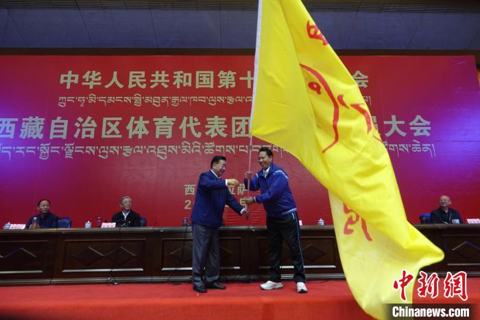 西藏自治區(qū)副主席甲熱·洛桑丹增授代表團團旗，西藏自治區(qū)體育局局長尼瑪次仁接旗?！∪轿木?攝