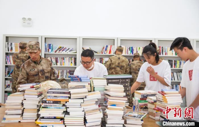 圖為志愿者們和邊防戰(zhàn)士整理圖書?！詵| 攝