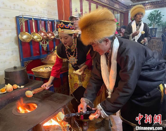 圖為人們在火上烤節(jié)日美食“結(jié)達”?！∪轿木?攝