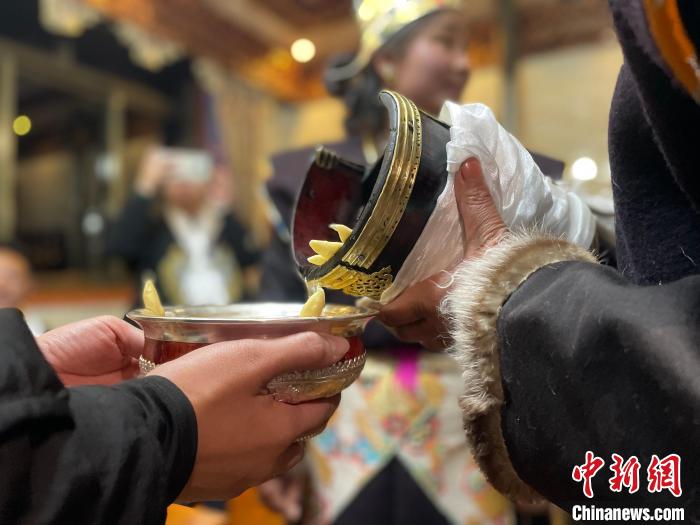圖為主人在碗中斟滿青稞酒?！∪轿木?攝