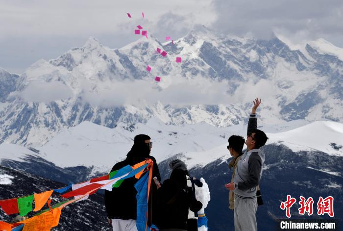 圖為5月14日，游客在西藏林芝色季拉山觀景臺(tái)拋灑“隆達(dá)”(風(fēng)馬旗，藏族民眾的一種祈福方式)?！±盍?攝